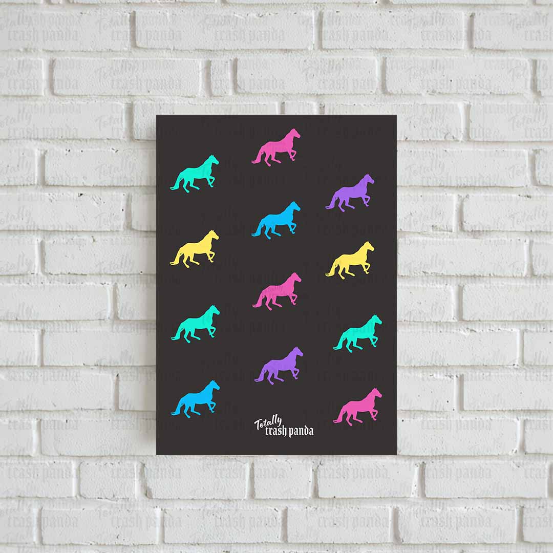A vertical art print featuring colorful horse silhouettes on a dark charcoal background, displayed against a white painted brick wall. The print includes the brand logo: 'Totally Trash Panda' at the bottom.