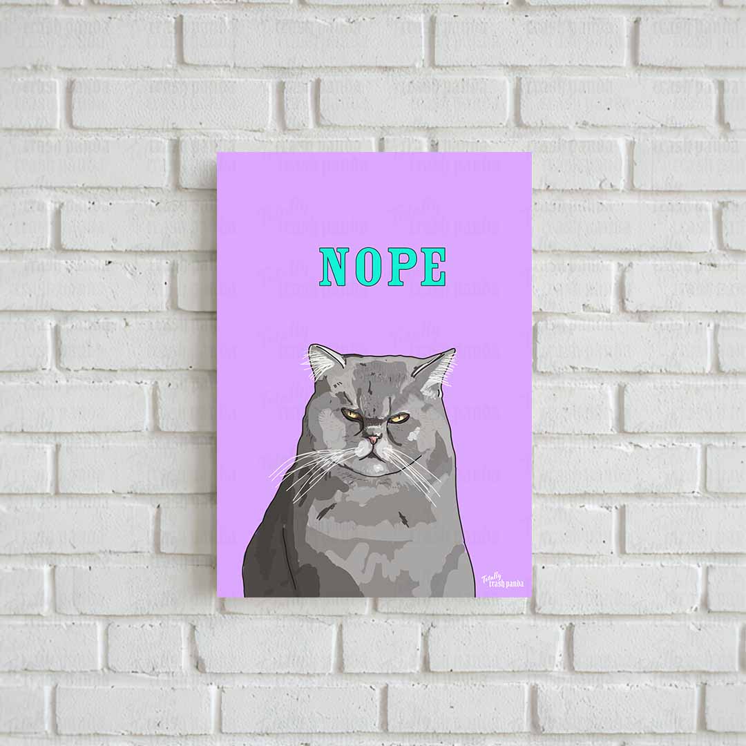 A vertical art print featuring a grumpy grey cat illustration on a lilac background with the word 'NOPE' in teal, displayed against a white brick wall. The brand logo 'Totally Trash Panda' is in the bottom right corner.