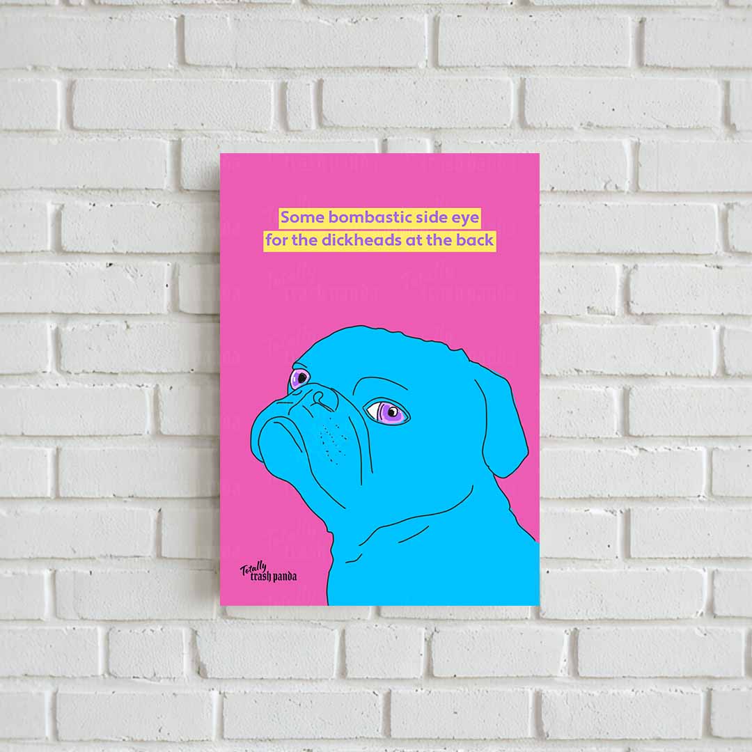 A vertical art print featuring a bright blue pug on a vivid pink background with the text 'Some bombastic side eye for the dickheads at the back' in yellow. The print is displayed on a white brick wall.